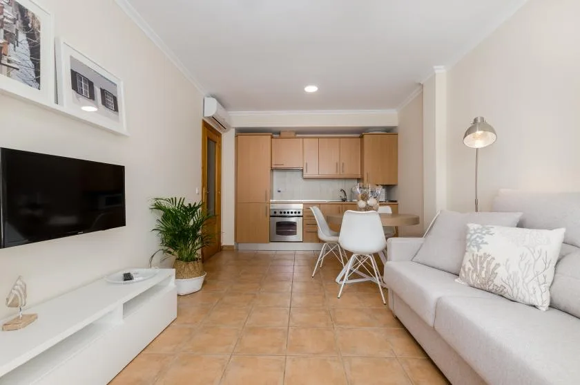 A living room with a sofa, television, and a dining area beside the kitchen.