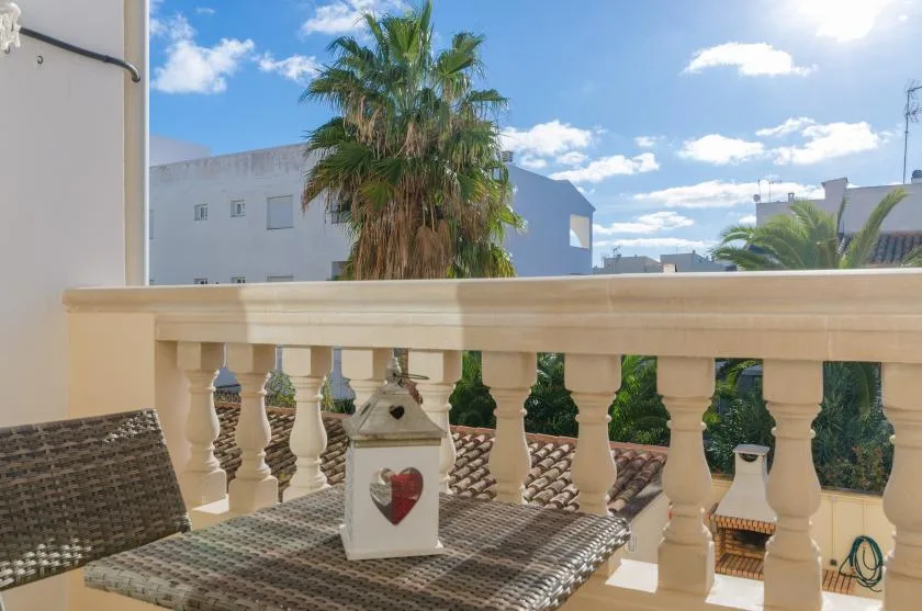 A balcony with patterned seating overlooks palm trees and nearby buildings.