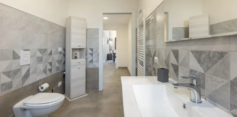 Un baño moderno con bañera, inodoro y azulejos geométricos en las paredes.