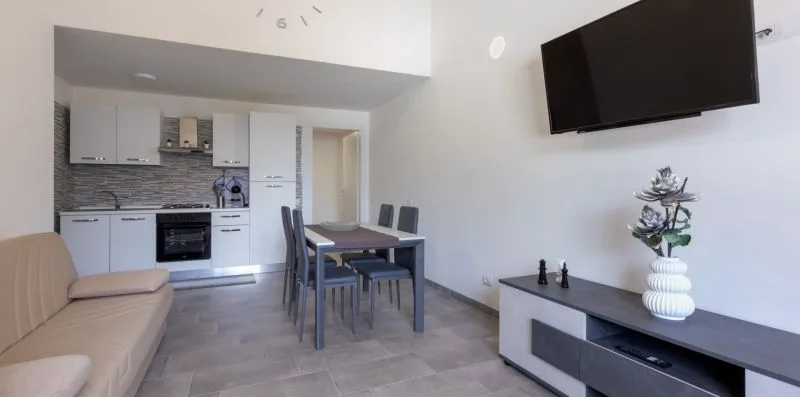 Una cocina compacta y zona de comedor con un televisor en la pared y asientos.