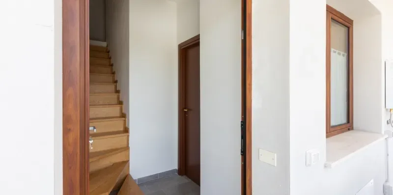 Un pasillo interior con una escalera y puertas de madera.