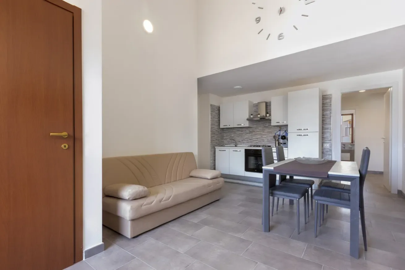 Una luminosa sala de estar y comedor se comunica con una cocina compacta, con sofá y mesa de comedor.