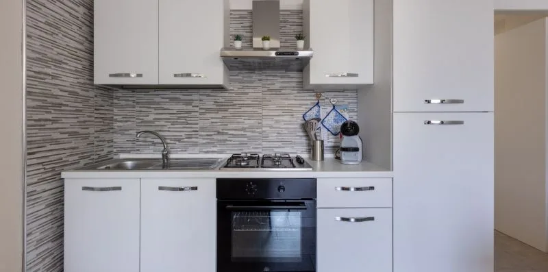 Una cocina moderna con gabinetes blancos, una estufa y un horno empotrado.