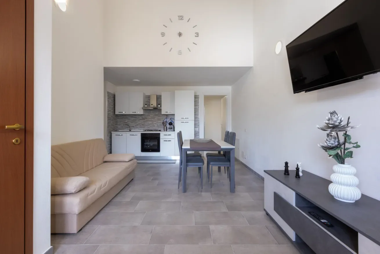 Una sala de estar y comedor se abre a una cocina compacta, con sofá y mesa.
