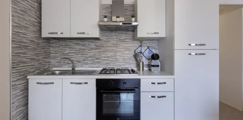 Una cocina moderna con gabinetes blancos, una estufa y un horno.