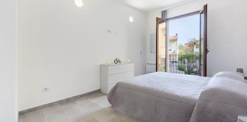 Un dormitorio luminoso con una cama y la puerta del balcón abierta.
