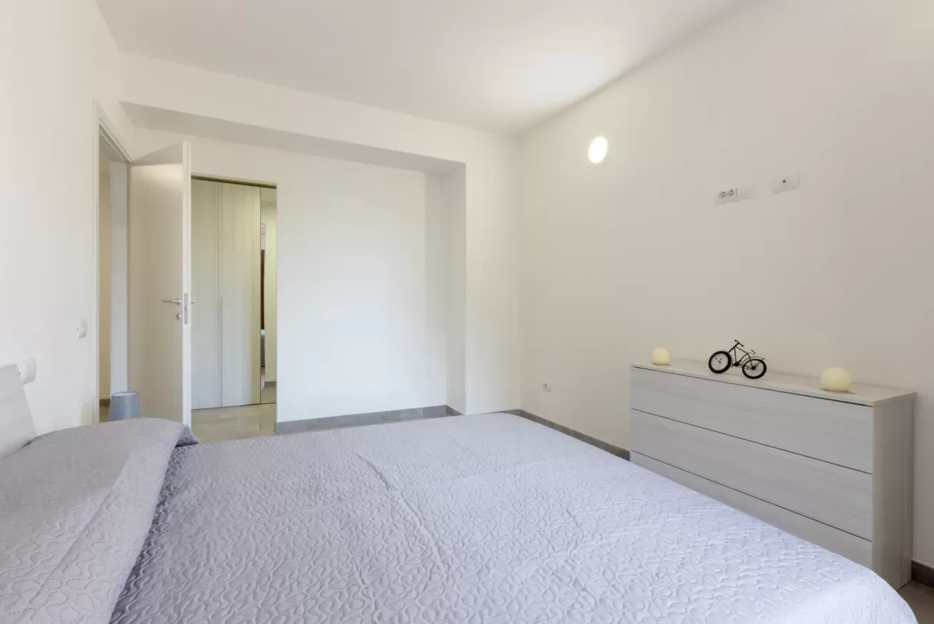 Dormitorio con una cama y una cómoda junto a una pared lisa.