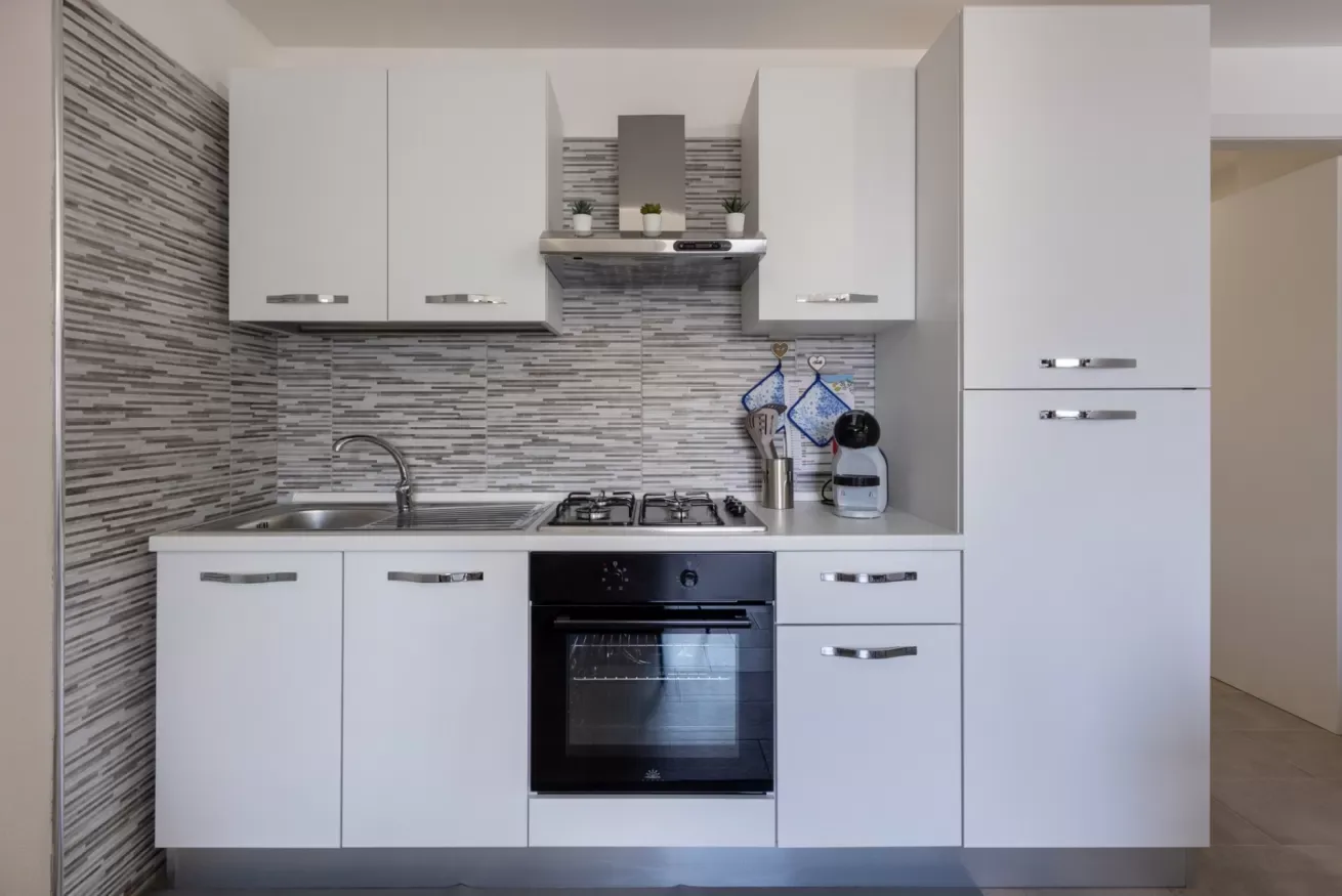Una cocina moderna con gabinetes blancos, una estufa y un horno.