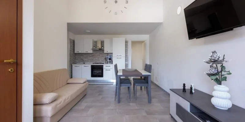 Una sala con comedor se abre a una cocina compacta y tiene un televisor en la pared.