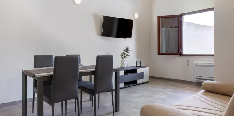 Comedor con mesa y sillas junto a un televisor montado en la pared.