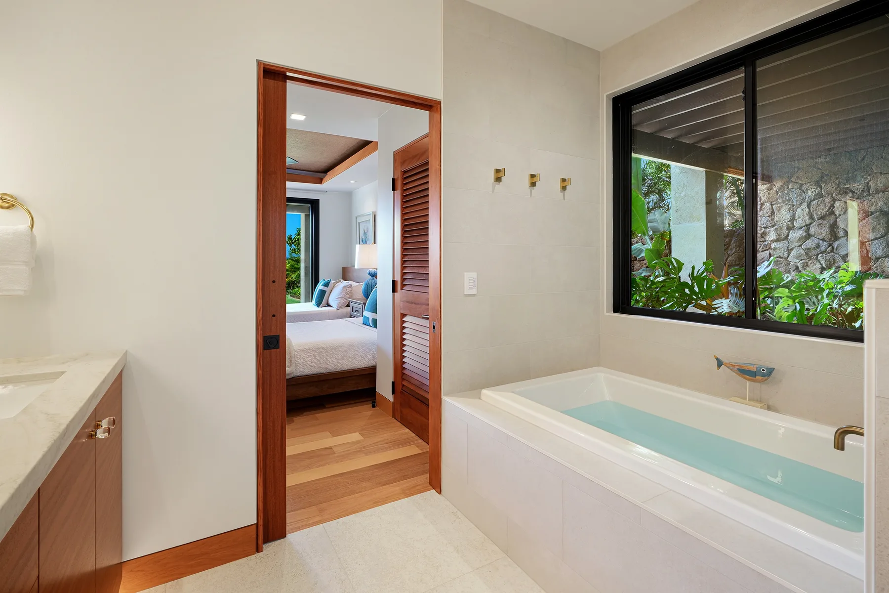 Un baño con una bañera empotrada junto a una ventana amplia.