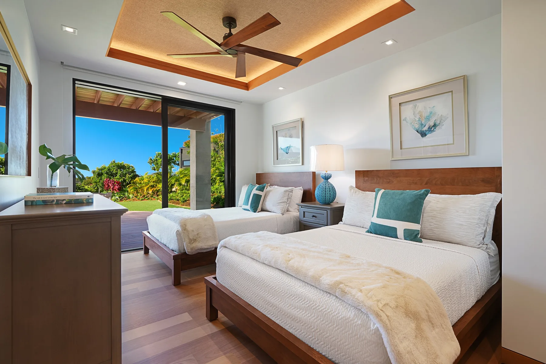 Dormitorio con dos camas y puertas corredizas de vidrio que dan a un jardín.