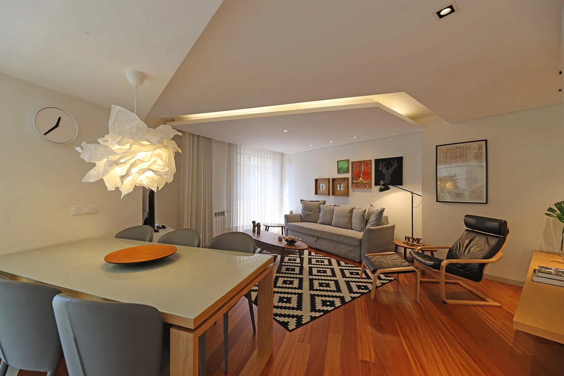 A living and dining area with seating around a patterned rug.