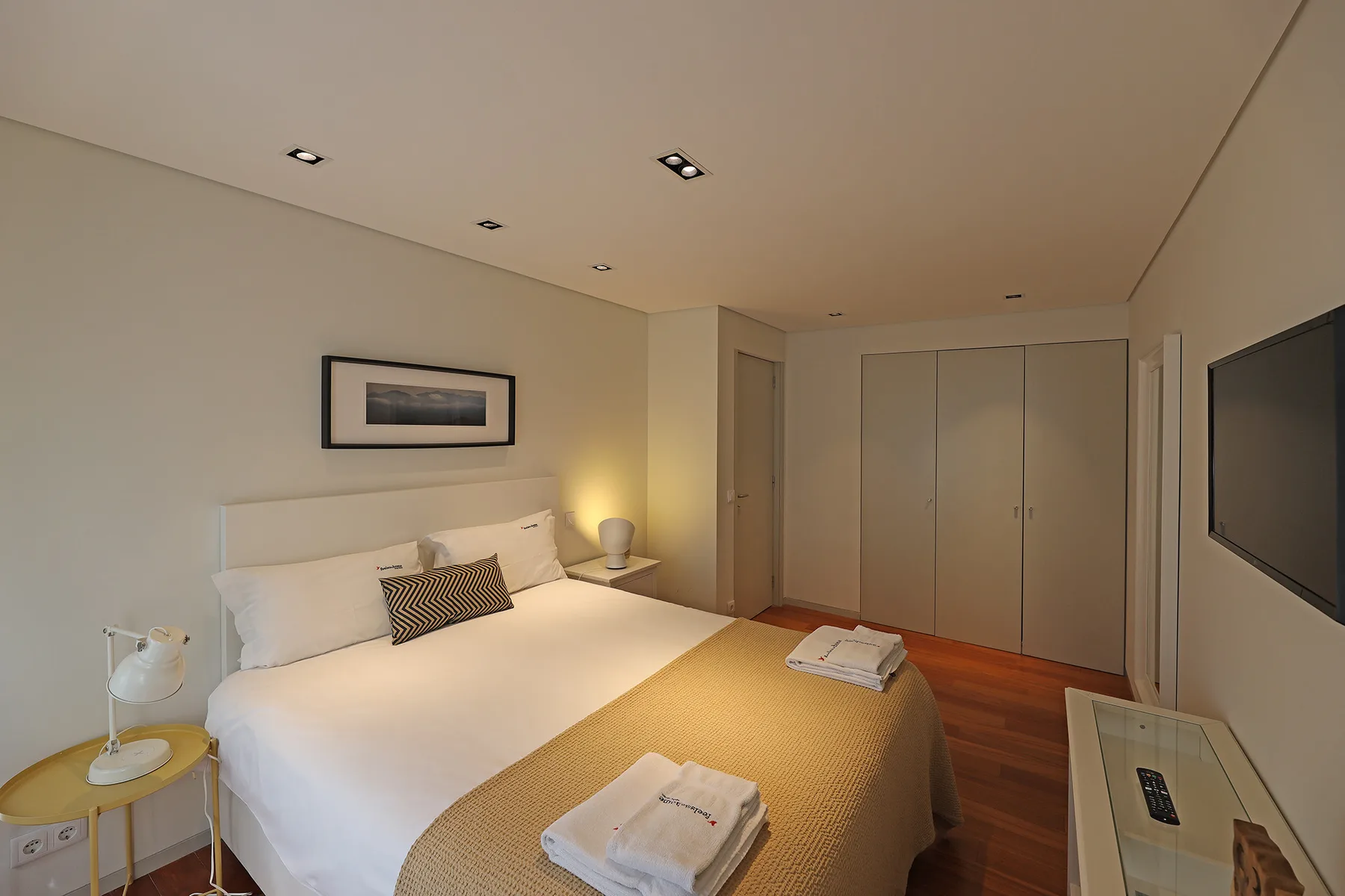 A bedroom with a double bed, bedside table, and built-in wardrobe.