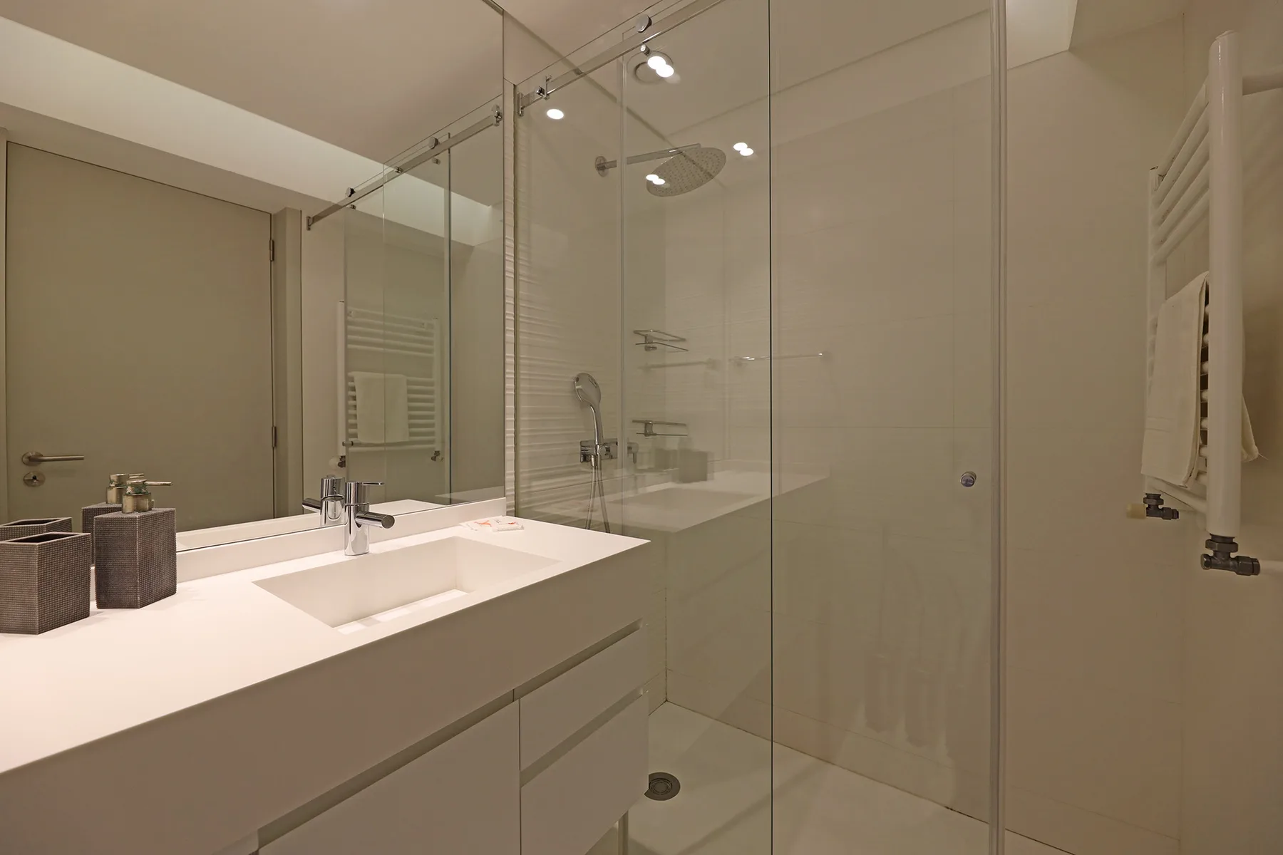 A bright bathroom with a long vanity and glass shower.