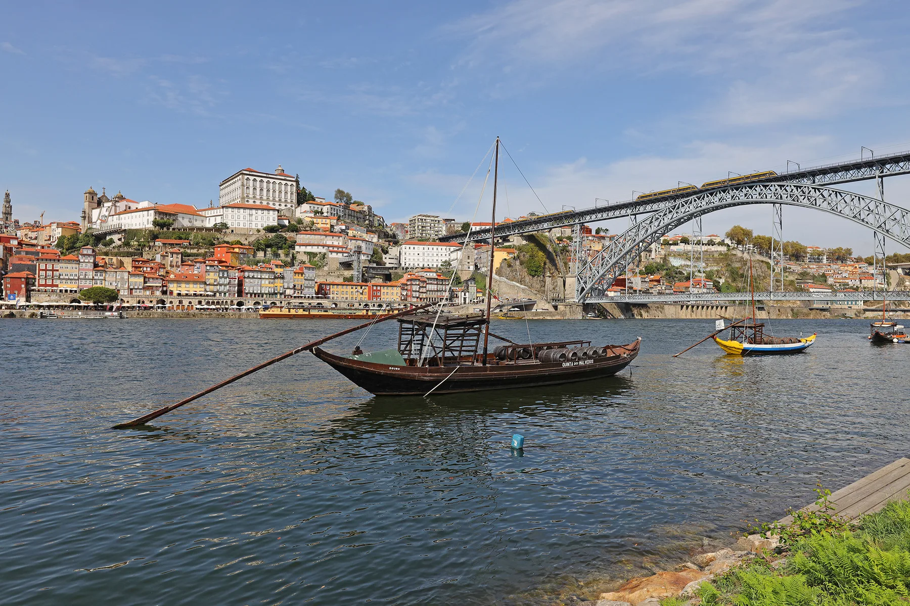 A river scene with a traditional boat in the foreground and a bridge beyond.