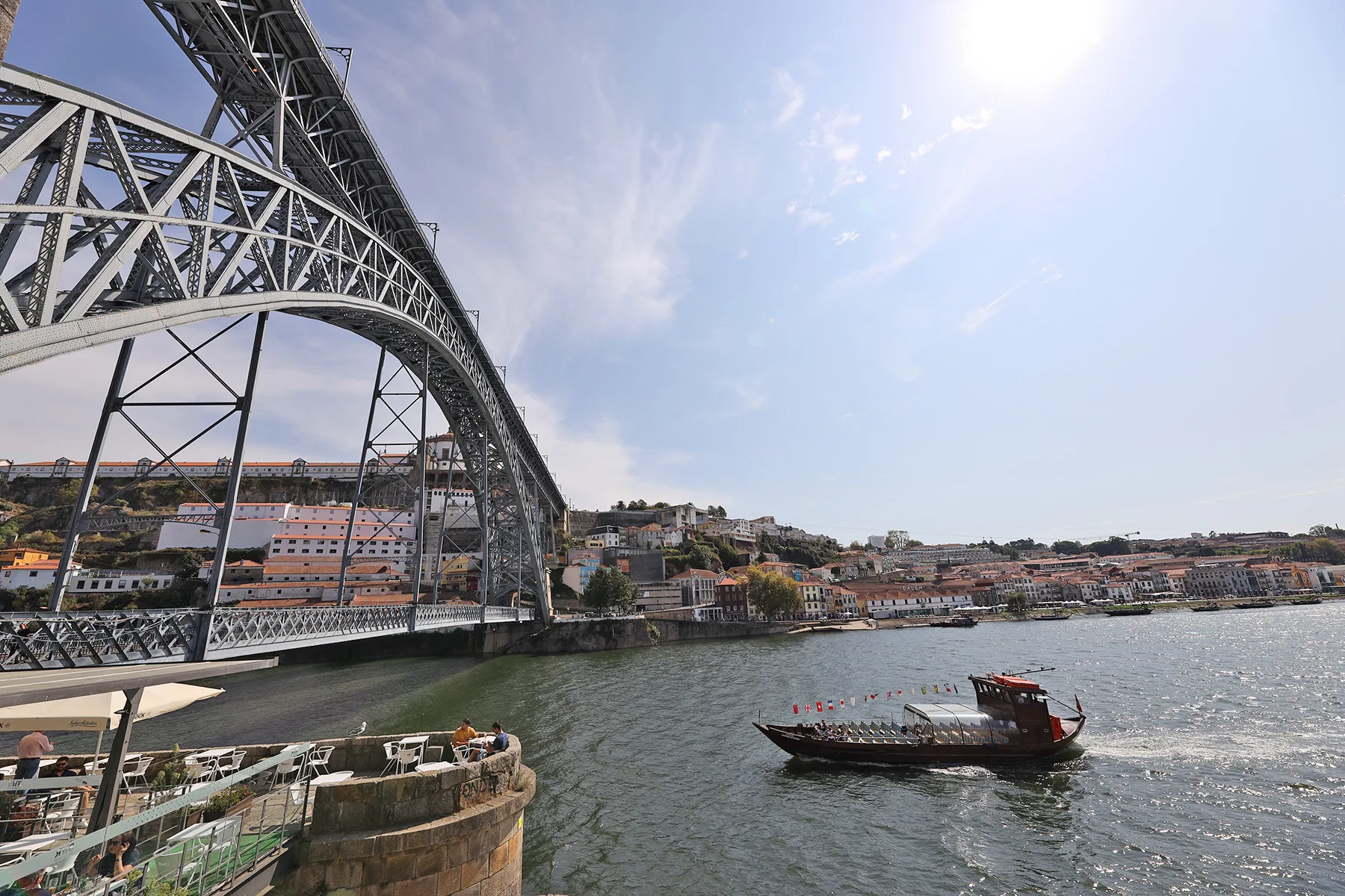 A river scene with a large steel bridge and a boat on the water.