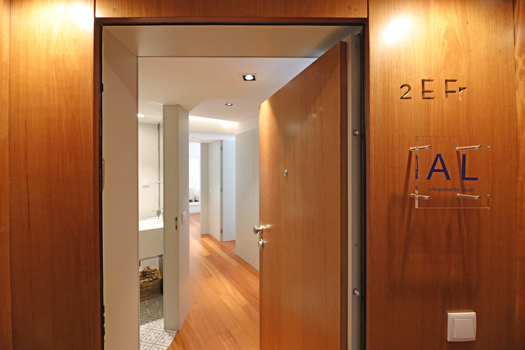An open wooden doorway reveals a bright interior hallway.