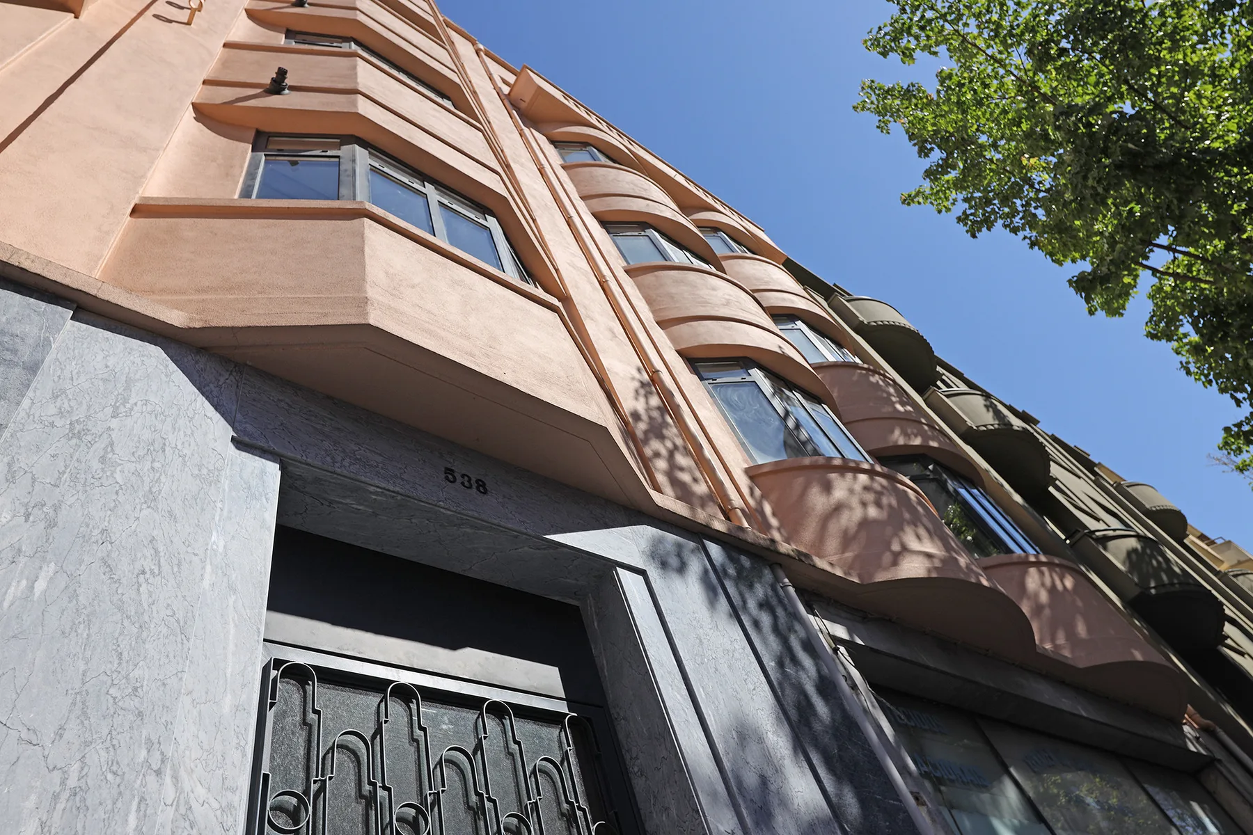 A multi-story apartment building facade with projecting balconies and a street-level entrance.