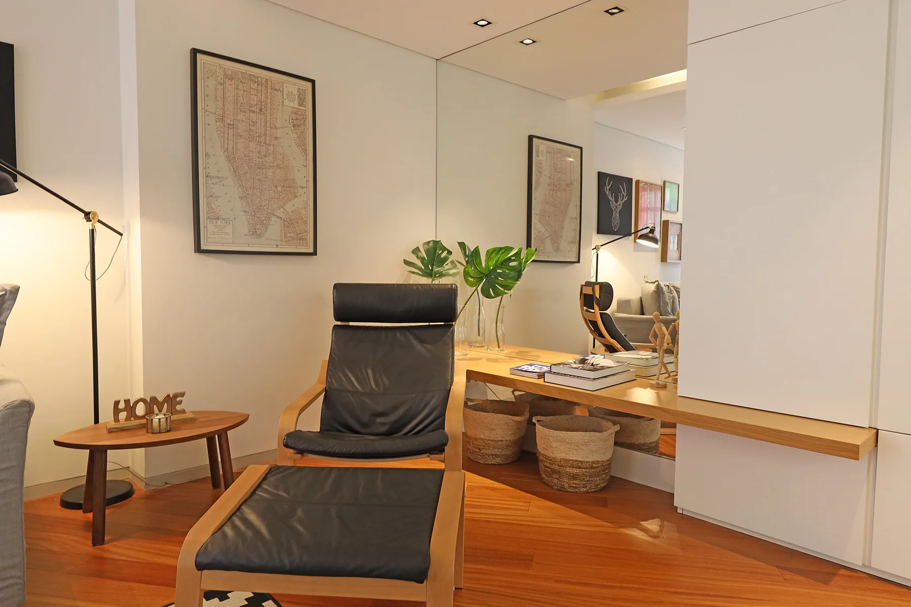 A modern living area has a lounge chair, wooden tables, and framed wall art.