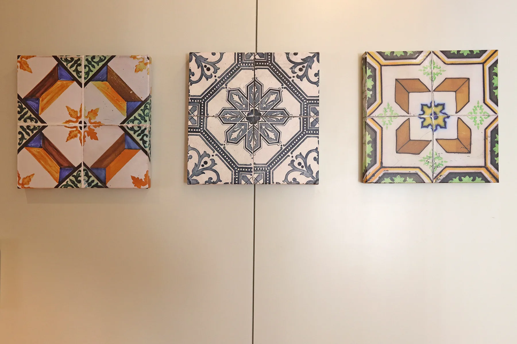 Three decorative patterned tiles hang on a plain light-colored wall.
