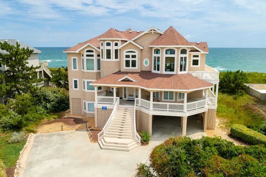 A large coastal house with several peaked roof sections and a broad front porch.