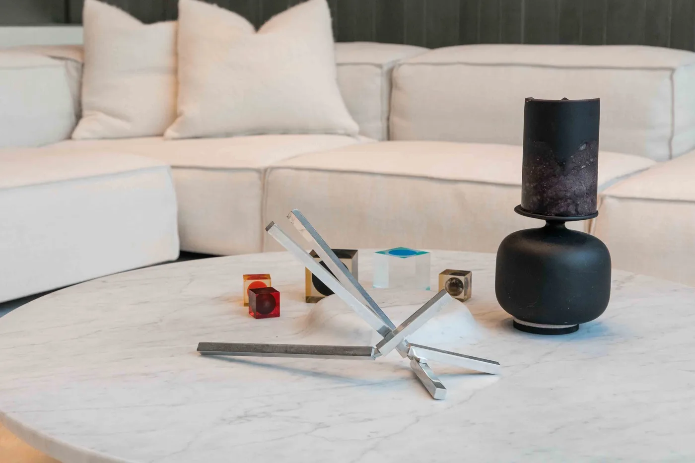 A living room seating area surrounds a round coffee table with decorative objects.