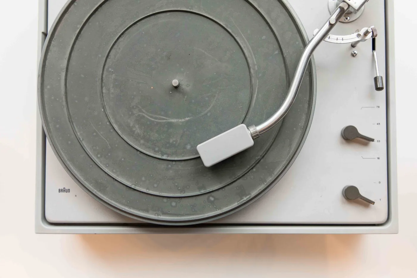 A turntable with a record sits against a plain light-colored background.