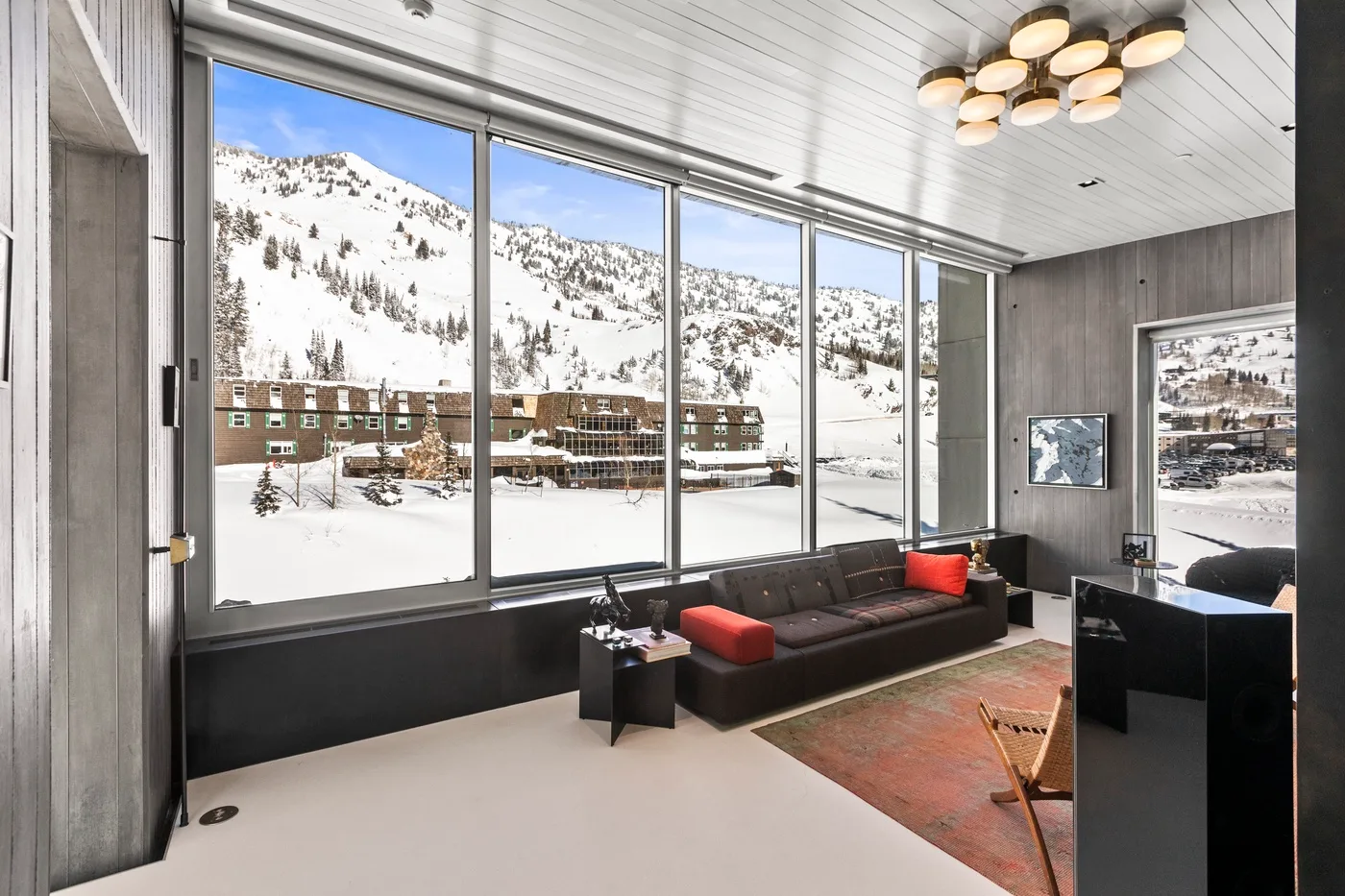 A modern living room with large windows overlooking a snowy mountain landscape.