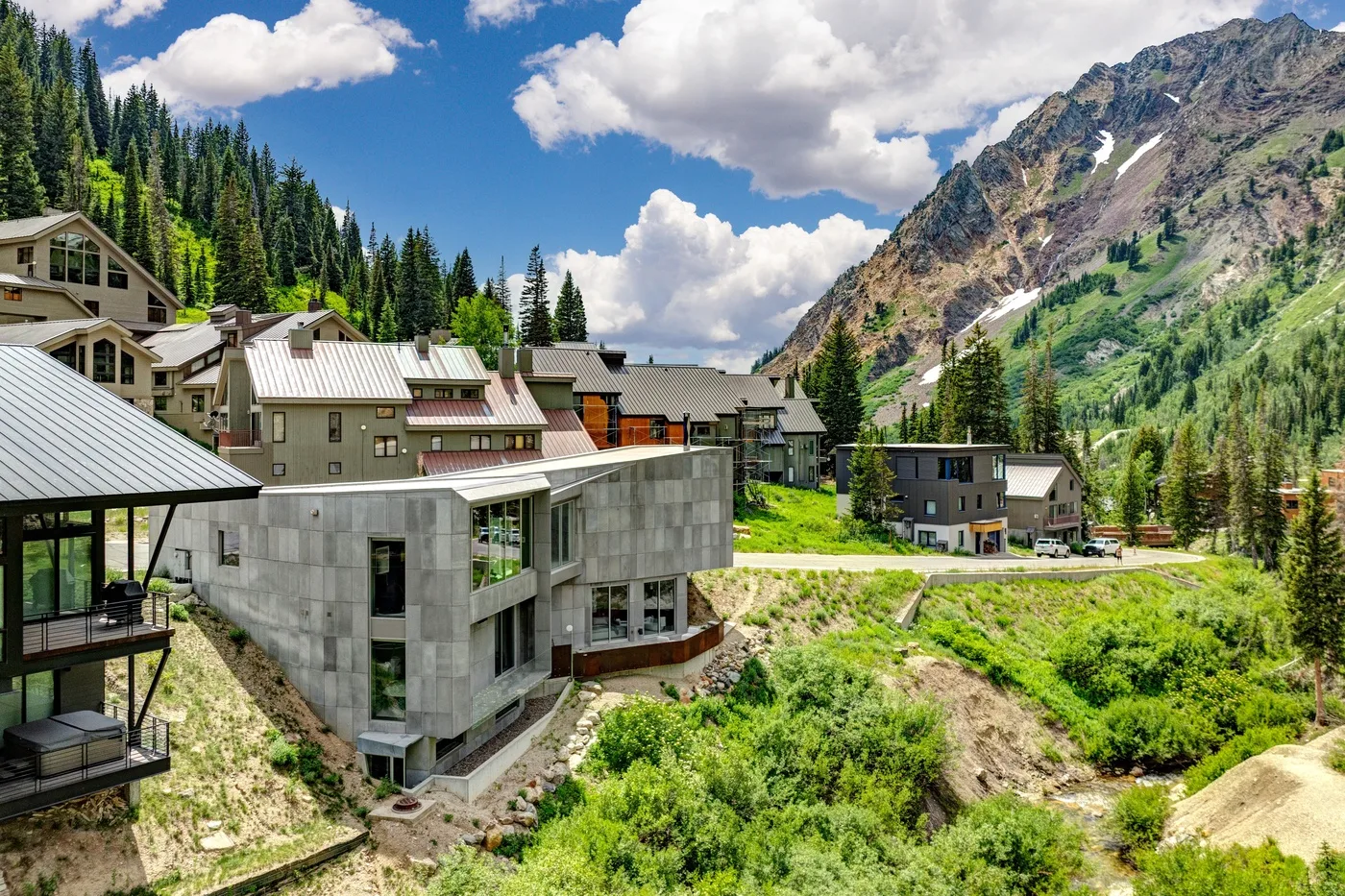 Mountain buildings sit among green slopes beneath a dramatic rocky peak.