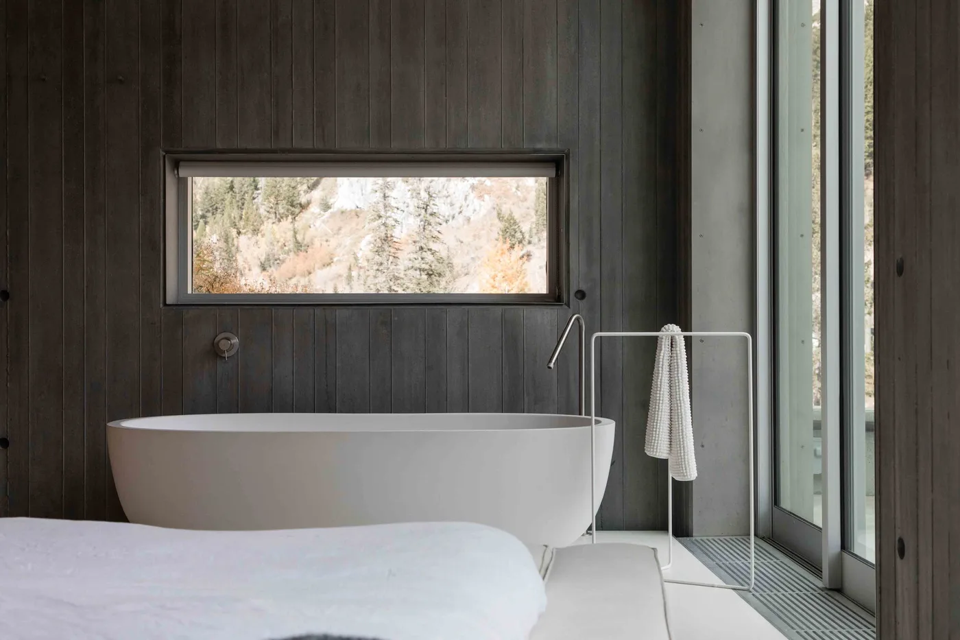 A modern bathroom with a freestanding bathtub beside large windows.