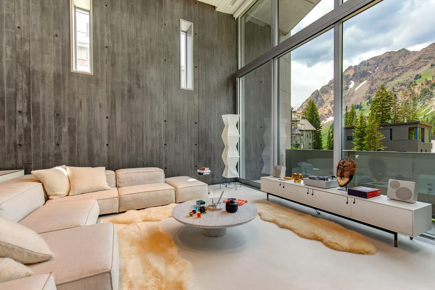 A spacious living room with seating, a low table, and large windows overlooking mountains.