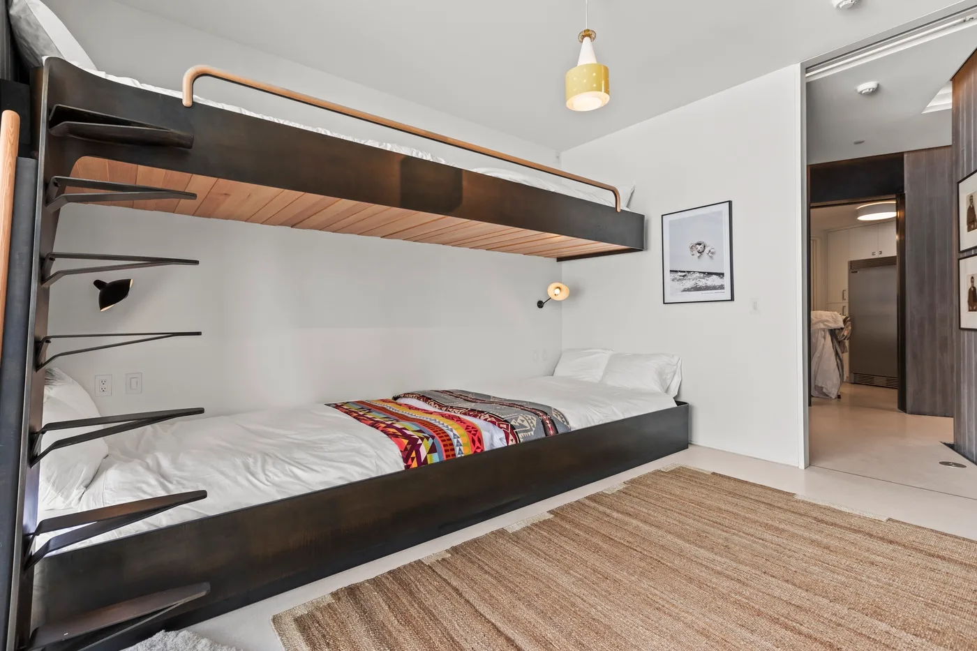 A bedroom with a bunk bed, patterned bedding, and a woven rug.