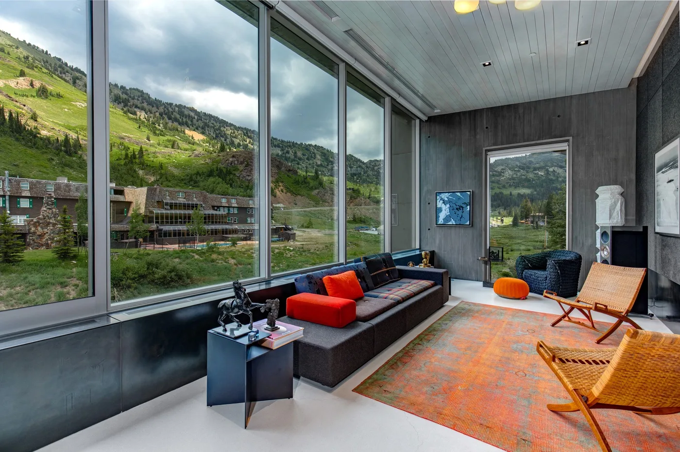 A bright lounge with large windows overlooking a green hillside.