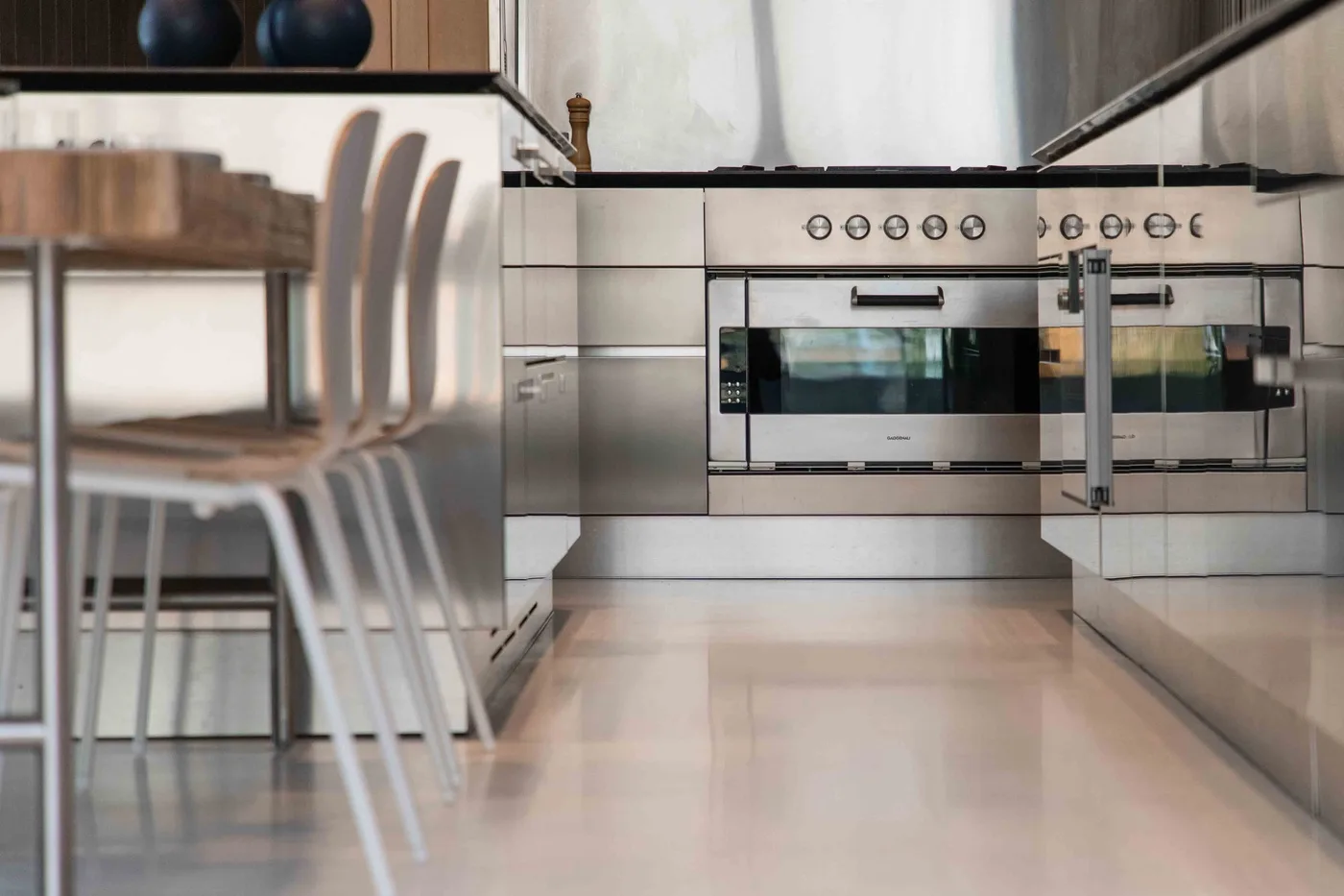 A modern kitchen with built-in ovens and bar seating along the counter.