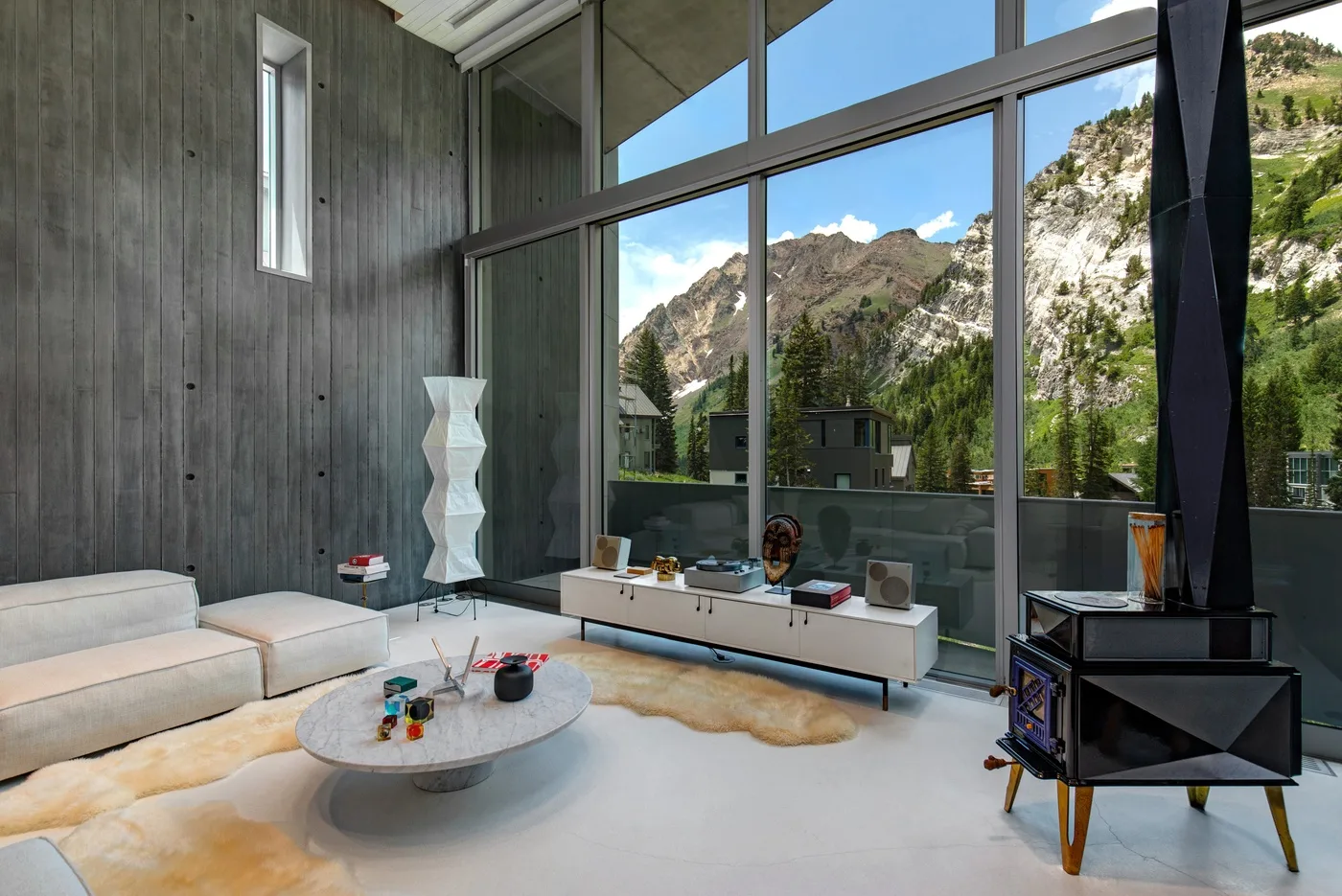 A modern living room with low seating and large windows overlooking a mountain landscape.