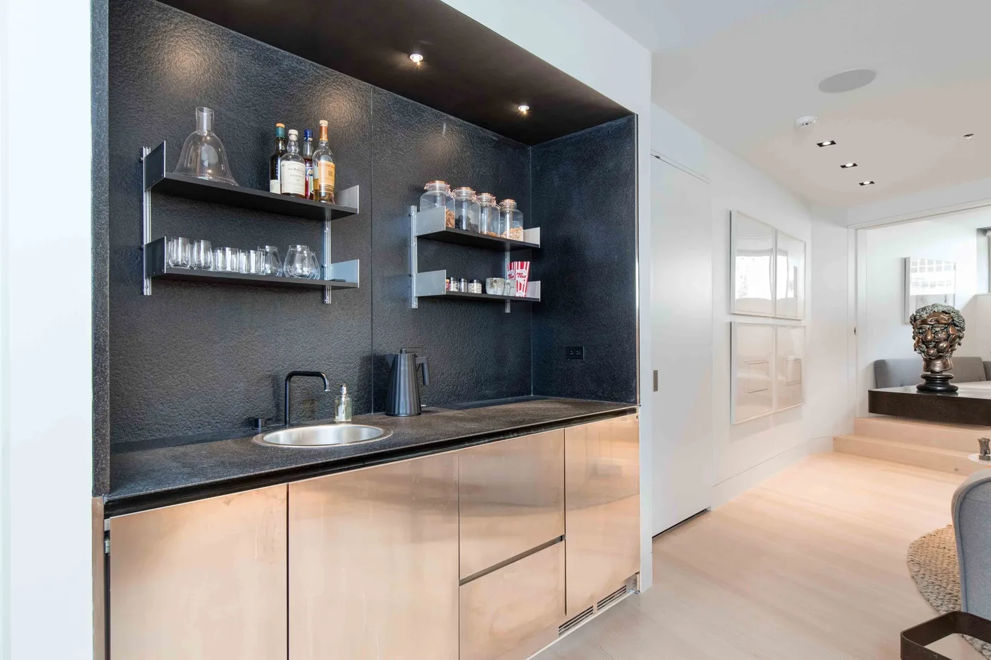 A modern kitchenette with open shelves and a dark countertop.