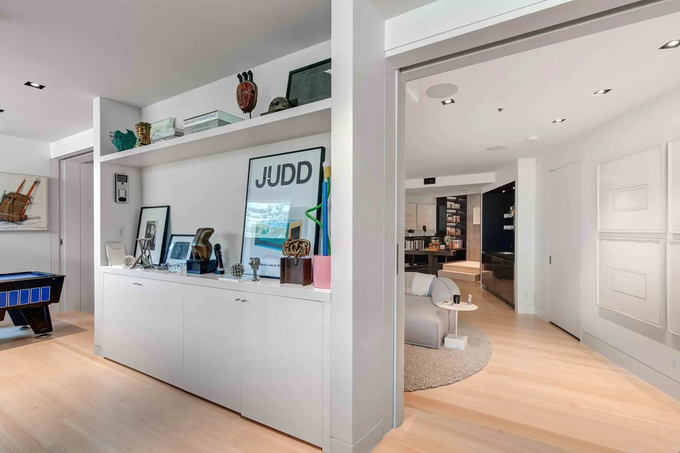 A bright modern interior shows a white display cabinet beside an open room.