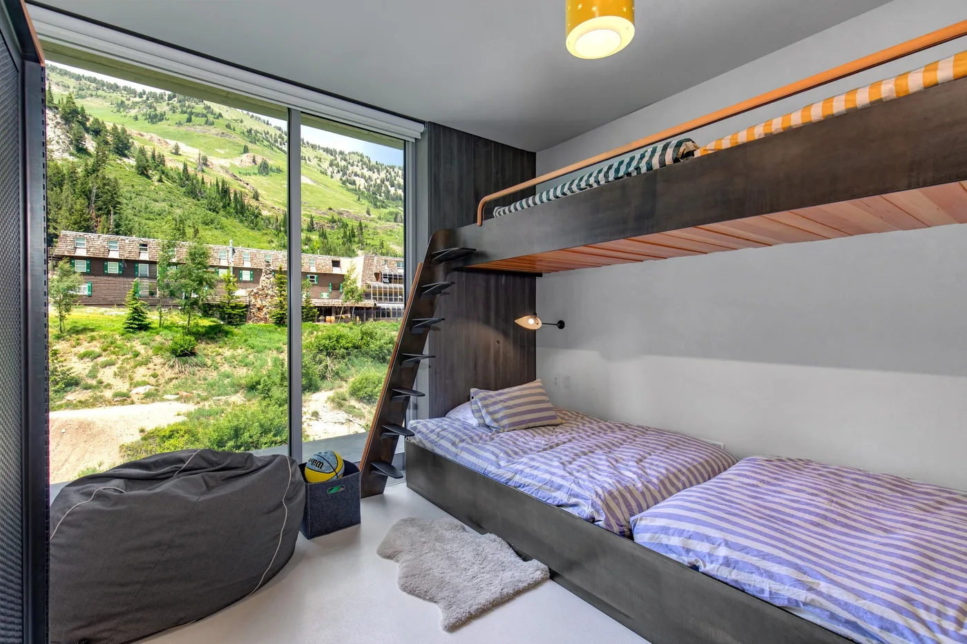 A bedroom with a lower bed beneath a raised bunk and a large window.