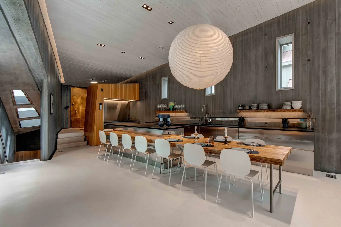 A spacious dining area with a long table, seating, and a kitchen counter.