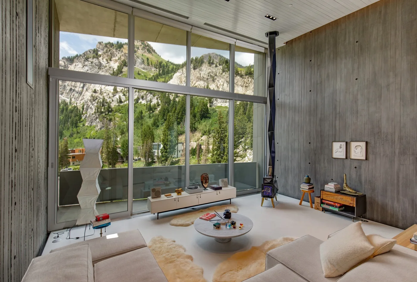 A modern living room with large windows overlooking a green mountain landscape.