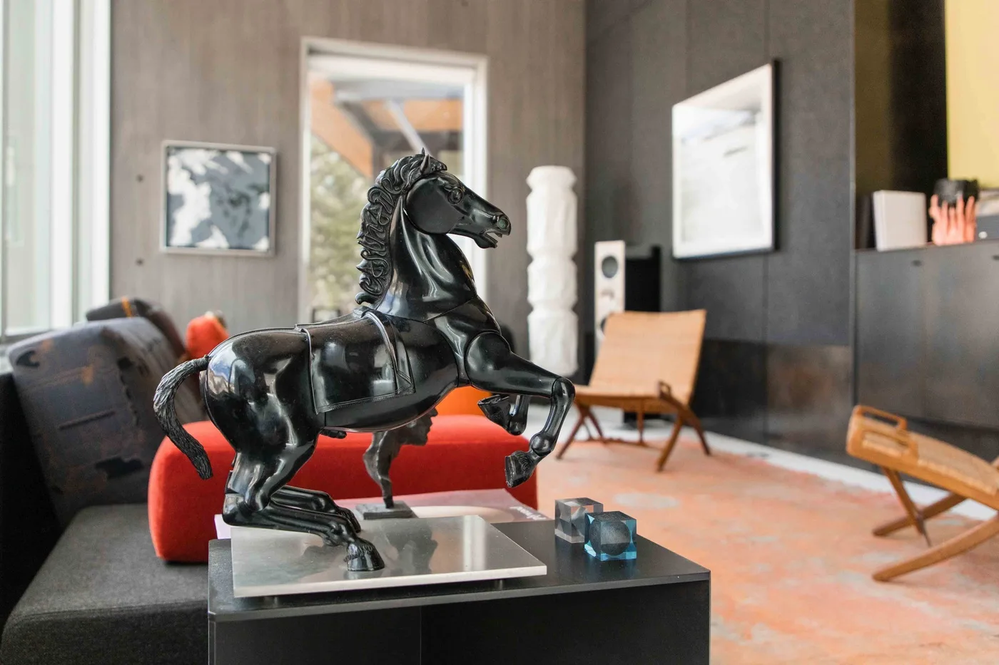A modern living room features a sculpted horse figure and lounge seating.