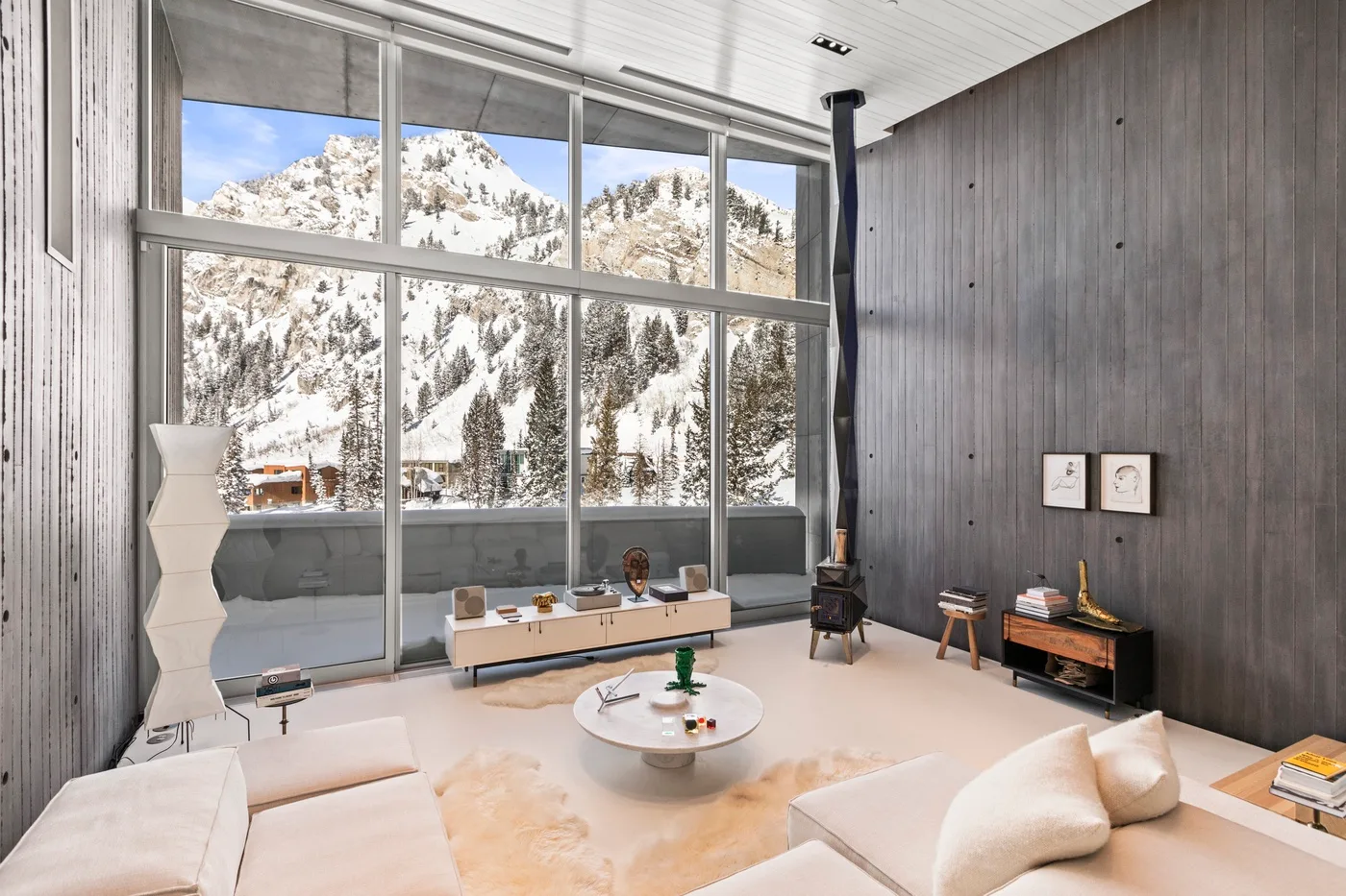 A modern living room with large windows overlooking snow-covered mountains.