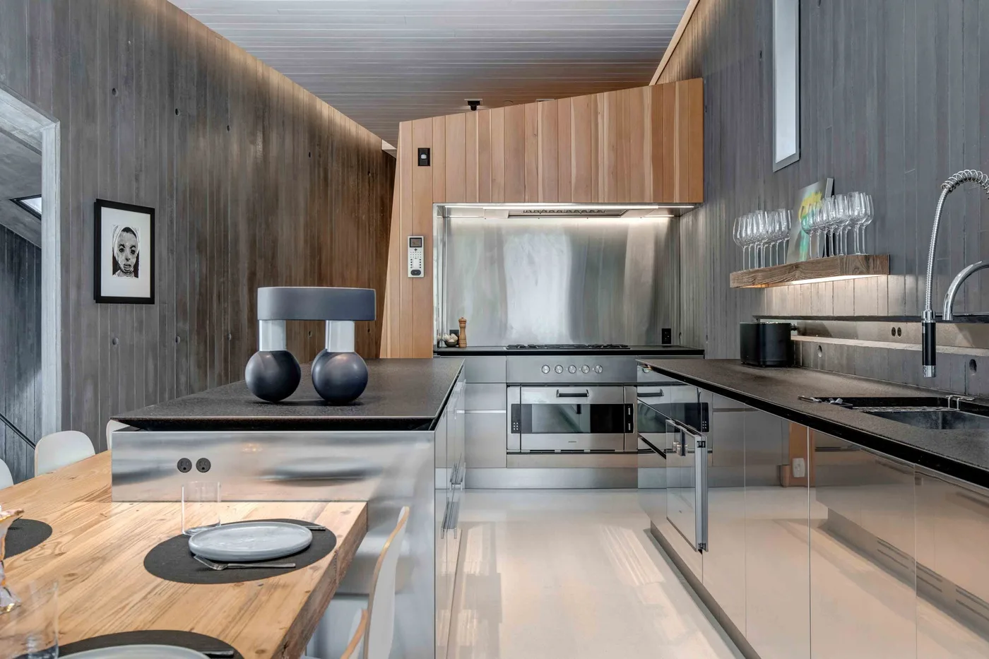 A modern kitchen with a central island, stainless-steel appliances, and wood cabinetry.