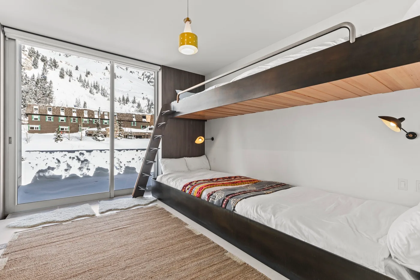 A bedroom with a bunk bed and a large window overlooking a snowy landscape.