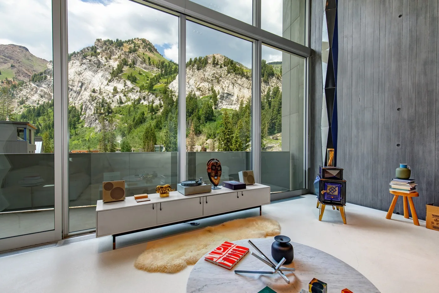 A bright living area with floor-to-ceiling windows overlooking a forested mountain landscape.