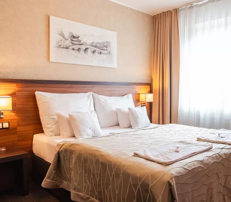 Double hotel room with a large bed and wooden headboard.