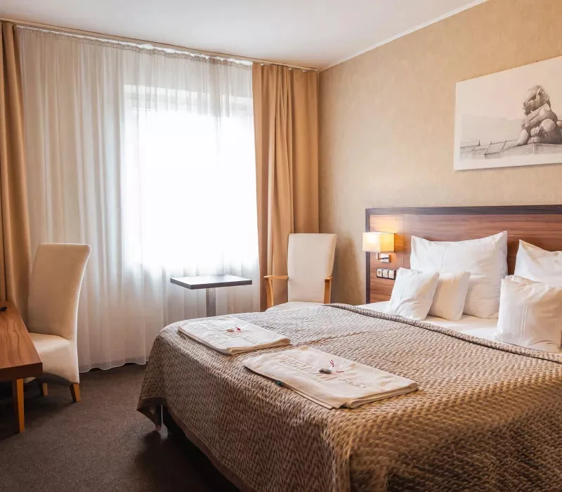 Hotel room with a double bed, wood furnishings and a work area.