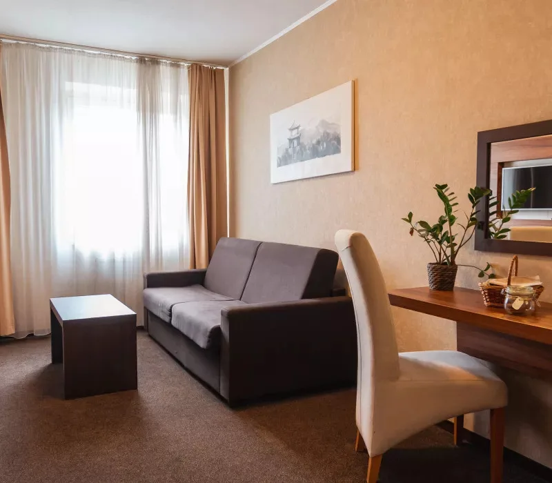 Hotel room sitting area with a sofa, desk and tea and coffee corner.