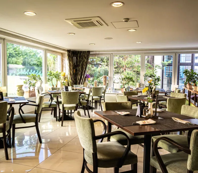 Hotel restaurant with set tables and large windows.
